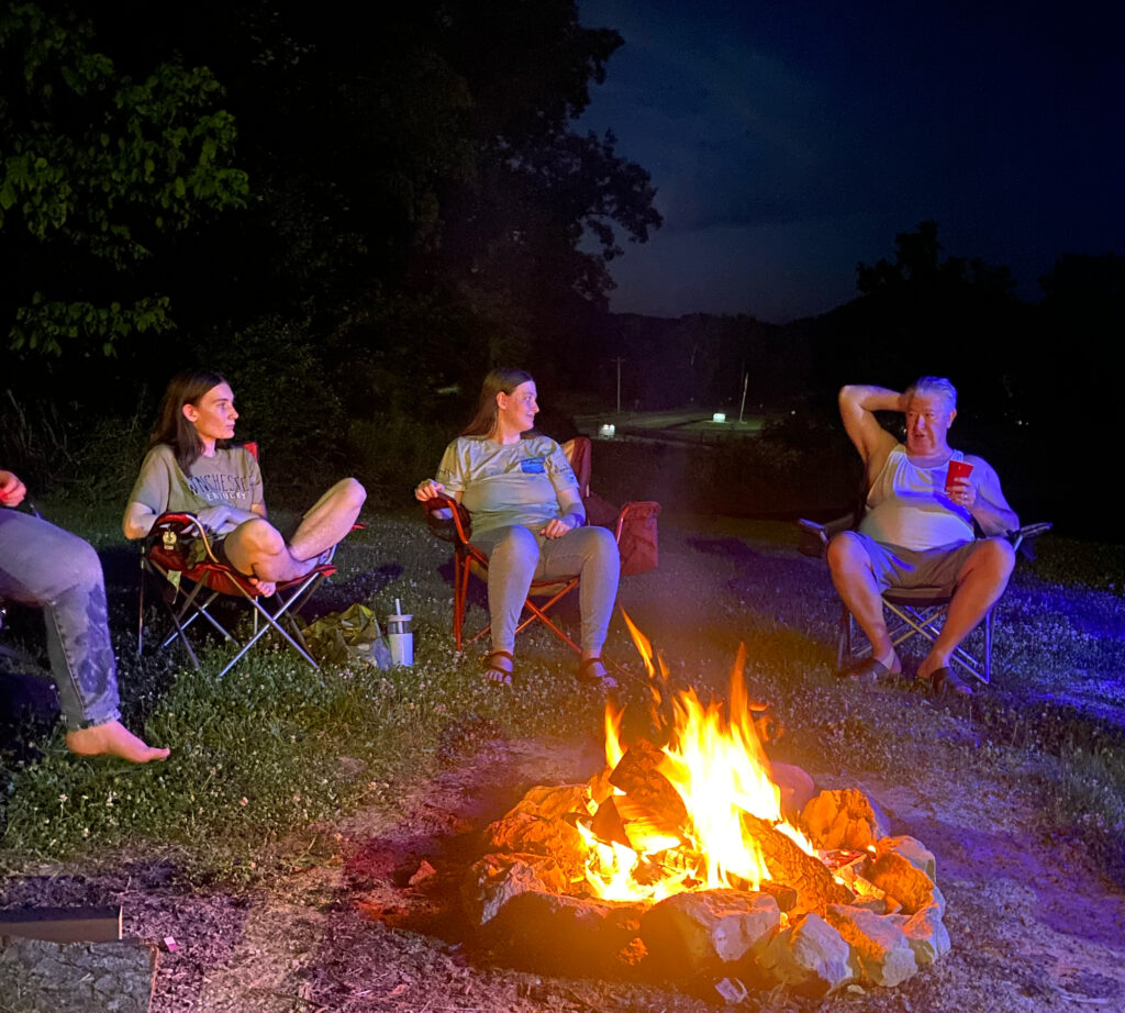 Family gathered around a campfire in the evening outside their motorhome