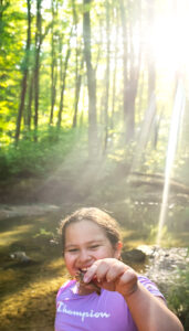 Young girl smiling and holding a crawdad in the creek