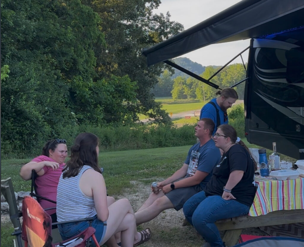 Family enjoying a casual gathering beside a motorhome with the awning out