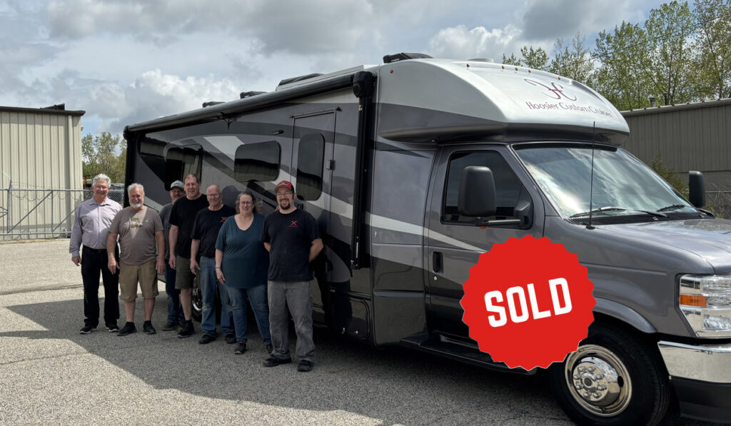 Midnight Grey Class B+ RV with owners standing outside
