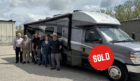 Midnight Grey Class B+ RV with owners standing outside